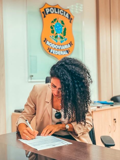 A person sitting at a desk signing a document
Description automatically generated